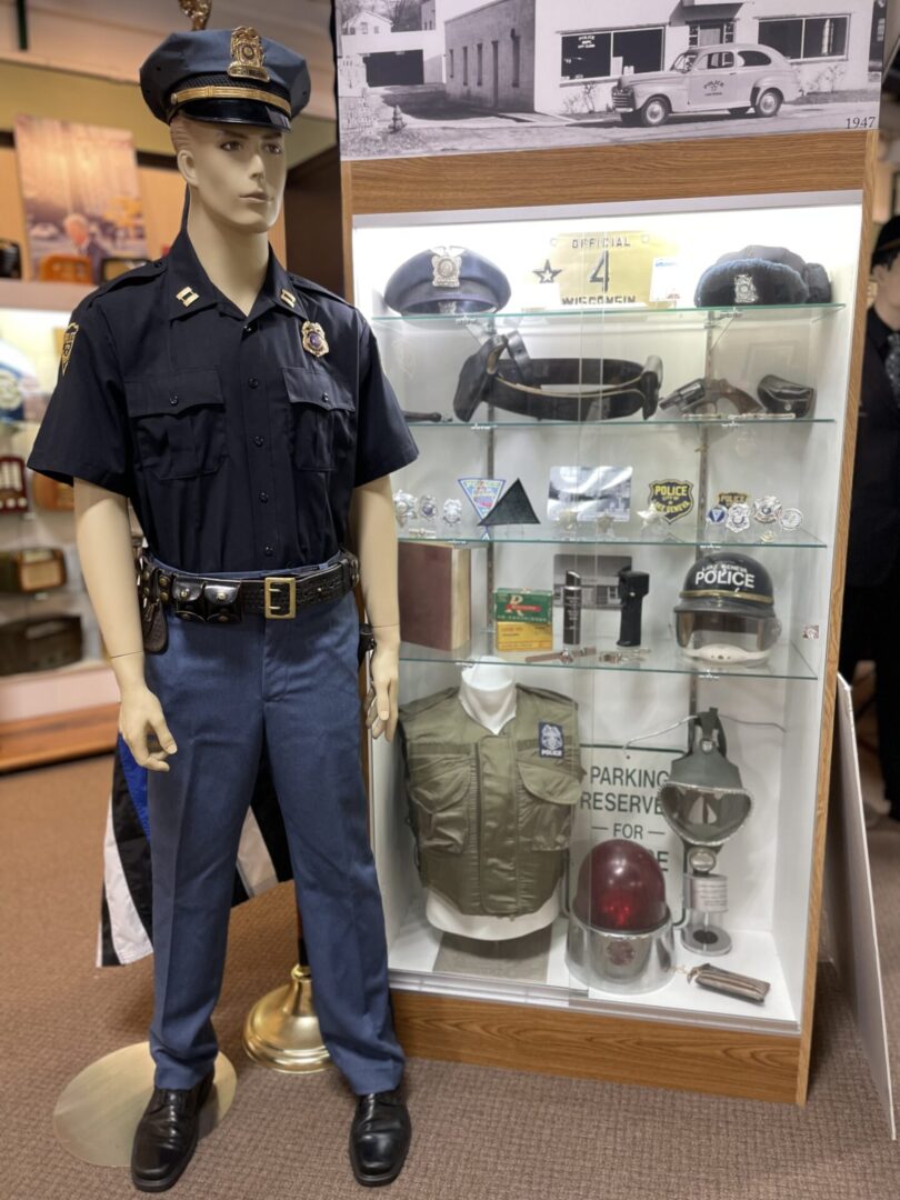 Mannequin in police uniform beside memorabilia display.