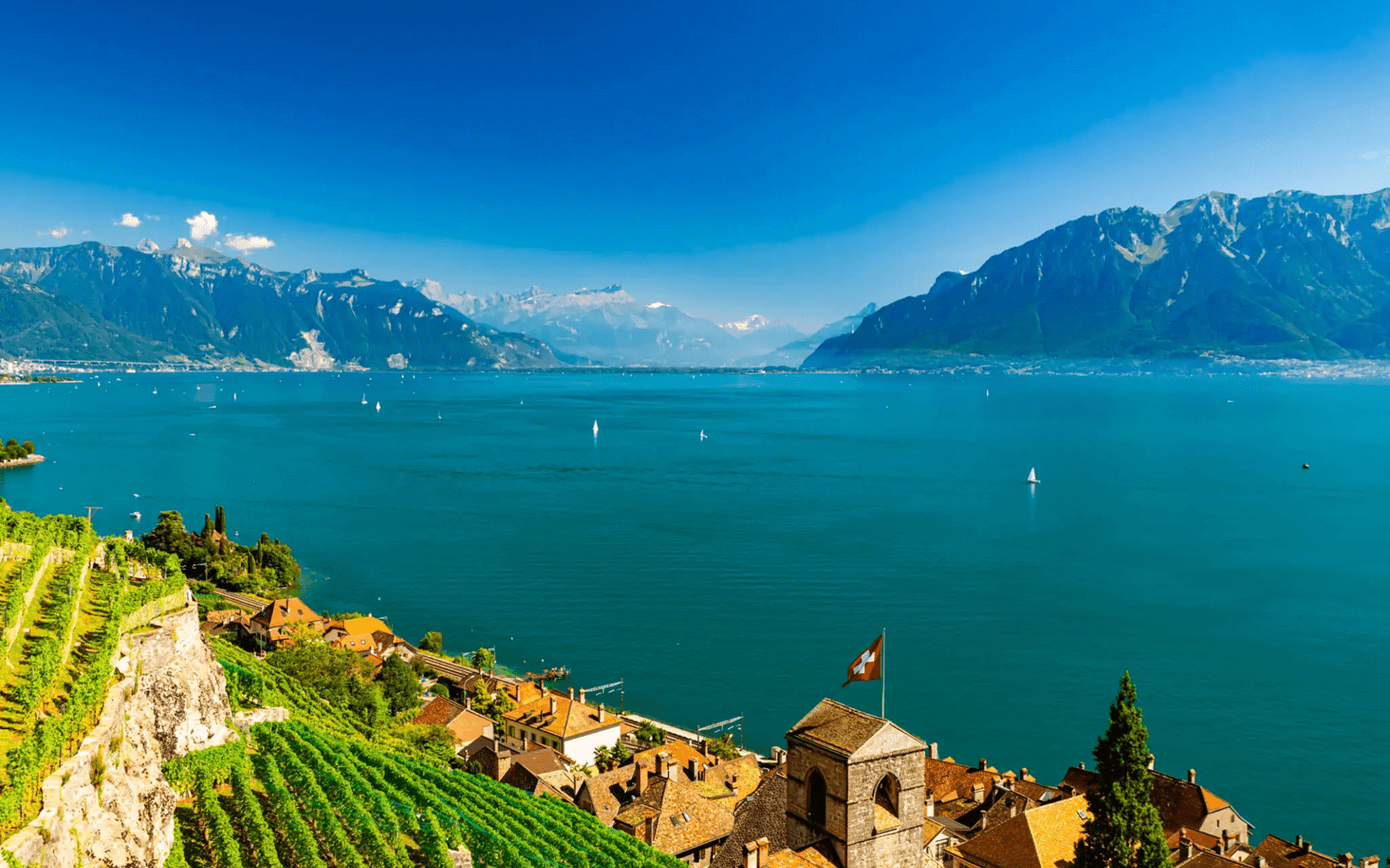 Scenic view of a lake surrounded by mountains under a clear blue sky.