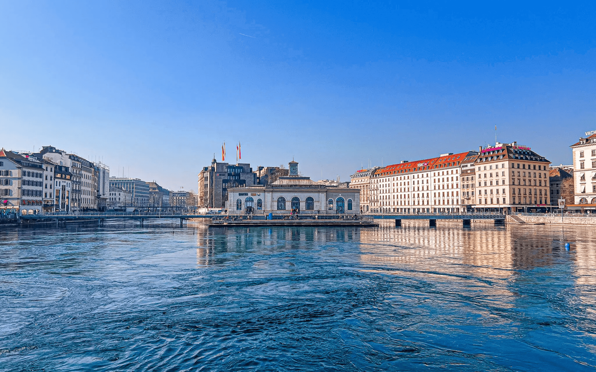 Scenic waterfront view with historic buildings under a clear blue sky.