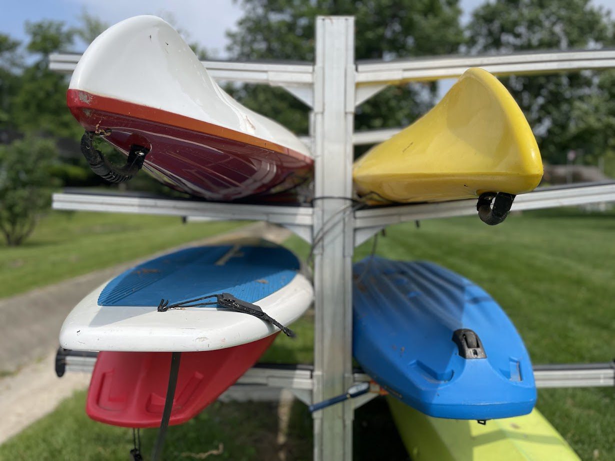 Colorful kayaks stacked on a metal rack outdoors.