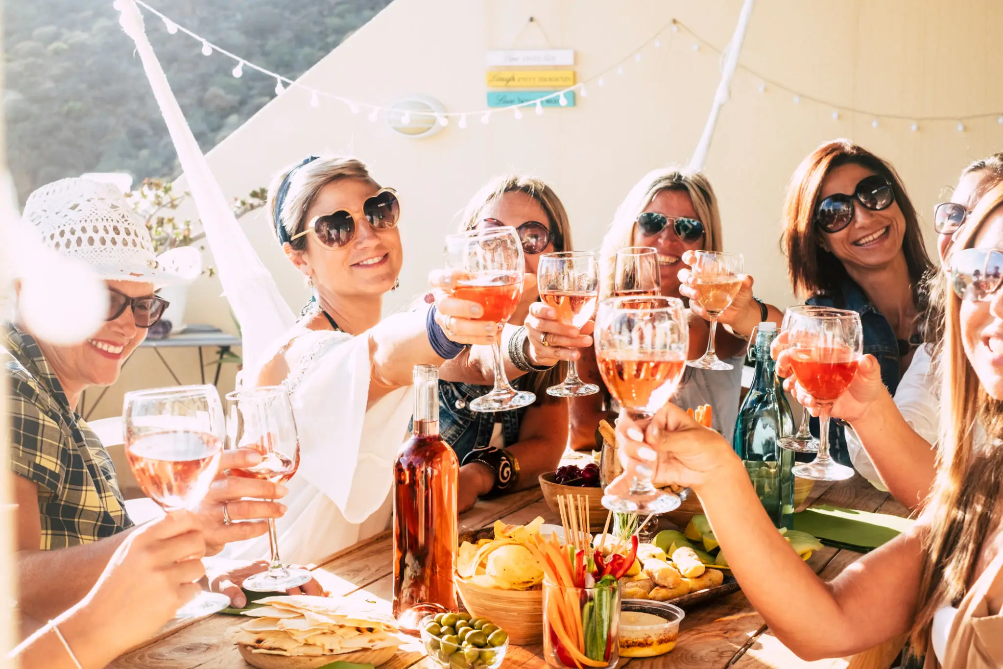 Friends enjoying a cheerful outdoor toast with drinks and food.