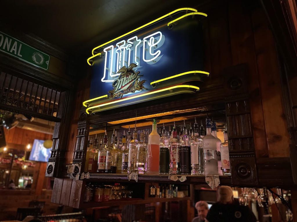 Neon Miller Lite sign glowing in a dim bar setting.