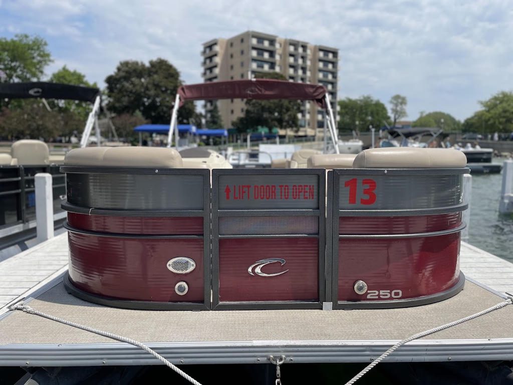 Maroon pontoon boat docked by the pier with building in background.