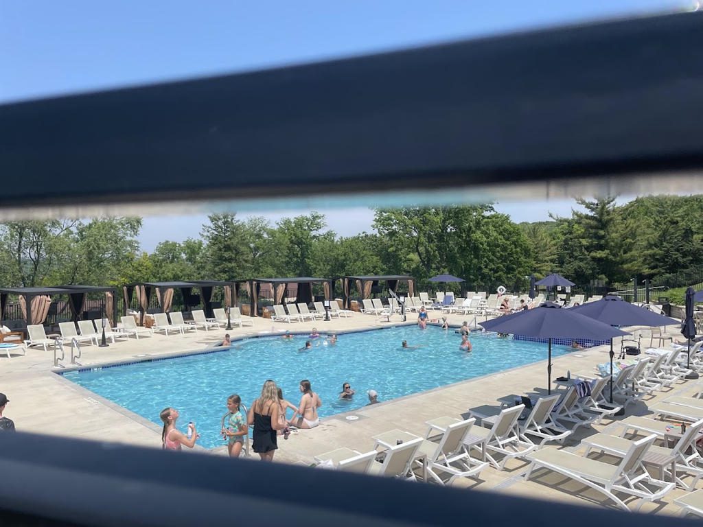People enjoying a sunny day at a large outdoor swimming pool.