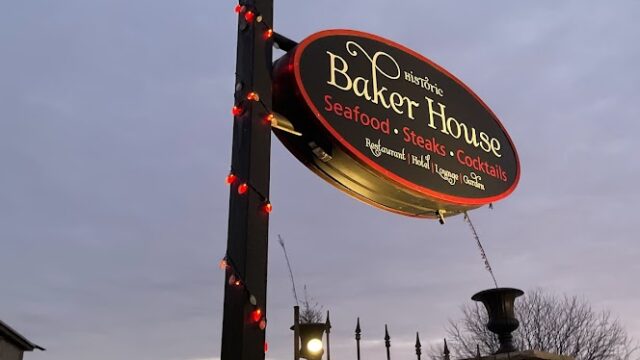 Signpost for The Bakery House in a park at dusk.