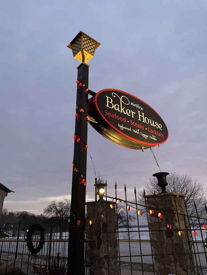 Signpost for The Bakery House in a park at dusk.