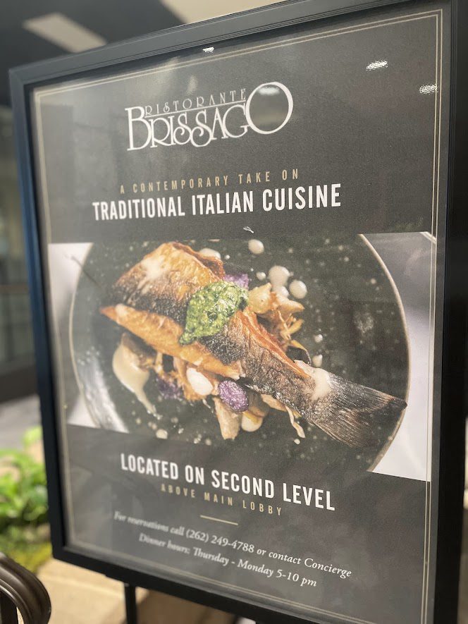 Signboard for Basilico Italian restaurant featuring traditional dishes and location info.