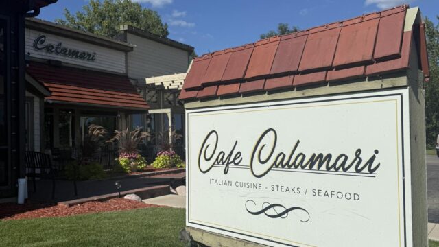 Sign for Cafe Calamari outside a sunny building with outdoor seating.