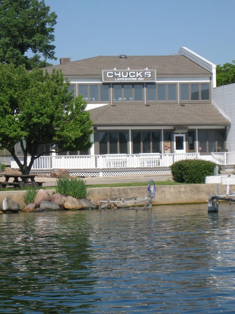 A lakeside building with a sign reading 'Chuck's' under a clear sky.