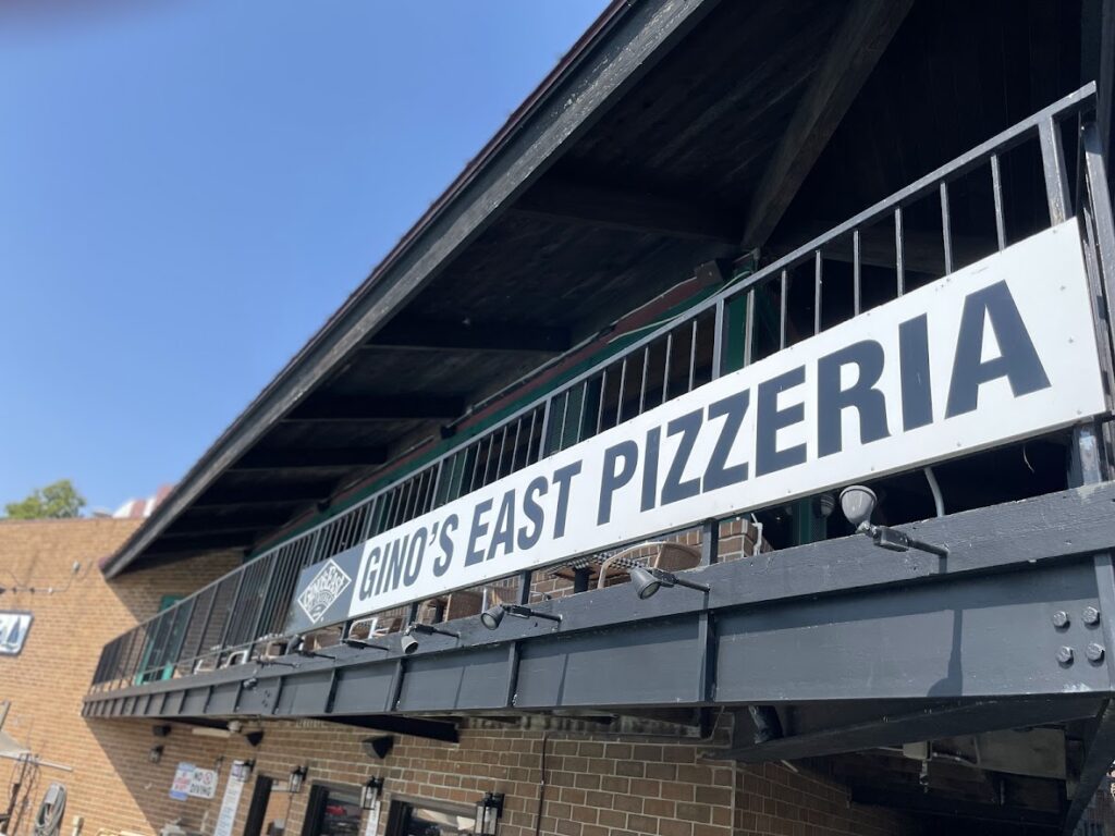 Signboard of Dino's East Pizzeria on a building.