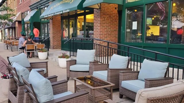 Cozy outdoor seating area with wicker furniture and cushions at a cafe.
