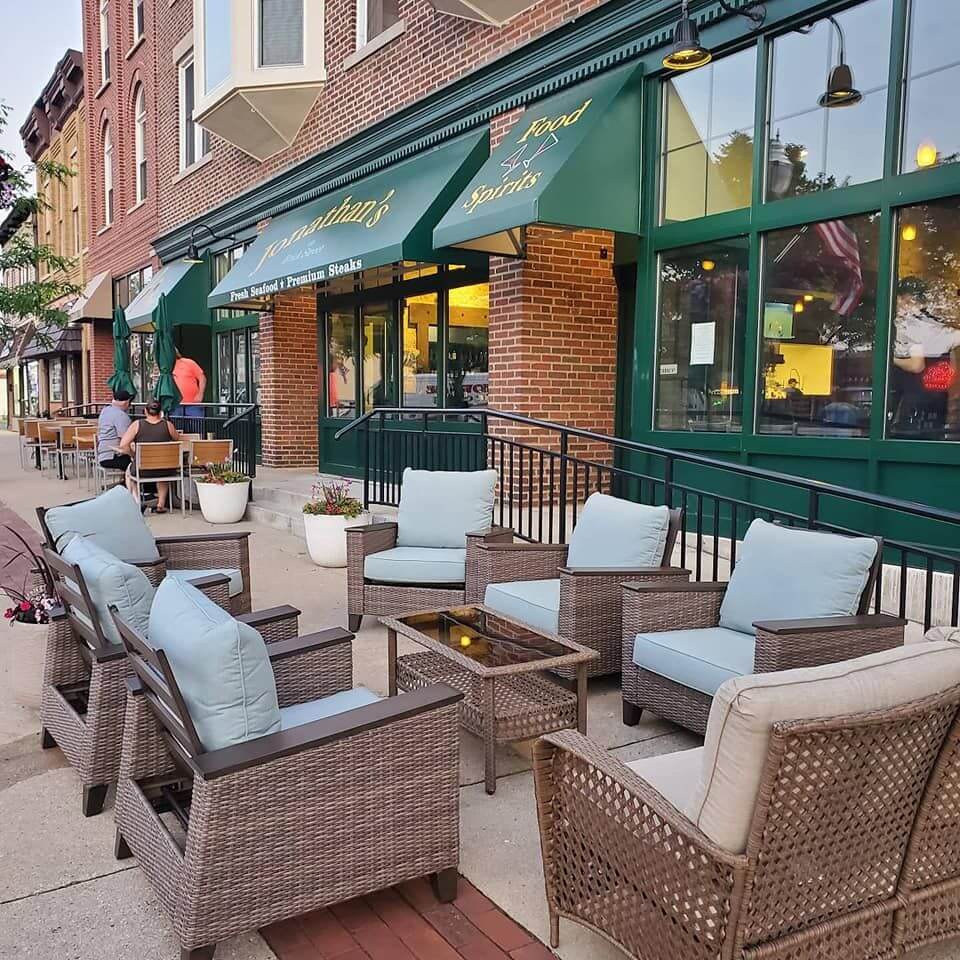 Cozy outdoor seating area with wicker furniture and cushions at a cafe.