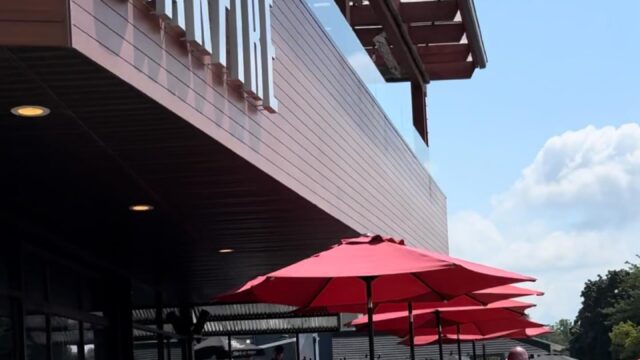Outdoor seating with red umbrellas at a cafe on a sunny day.