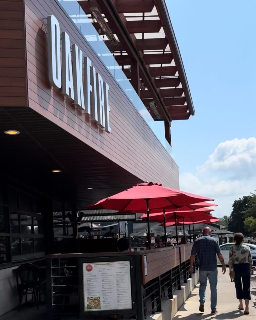 Outdoor seating with red umbrellas at a cafe on a sunny day.