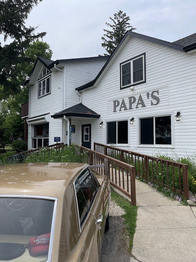 Exterior view of Papa's restaurant with a wheelchair ramp and parked car.