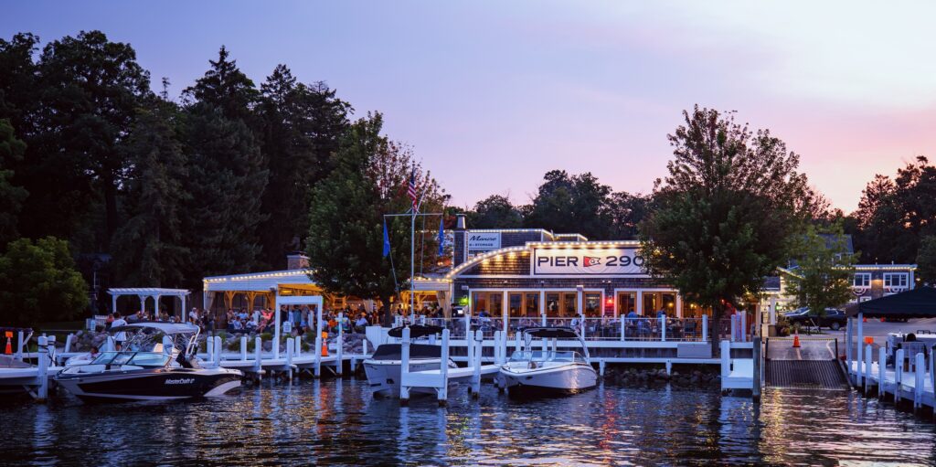 Lakeside restaurant with outdoor seating at sunset.