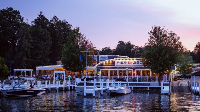 Lakeside restaurant with outdoor seating at sunset.
