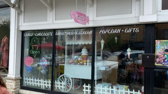 Exterior of a pet grooming shop with a sign and window decals.
