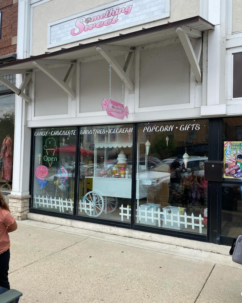 Exterior of a pet grooming shop with a sign and window decals.