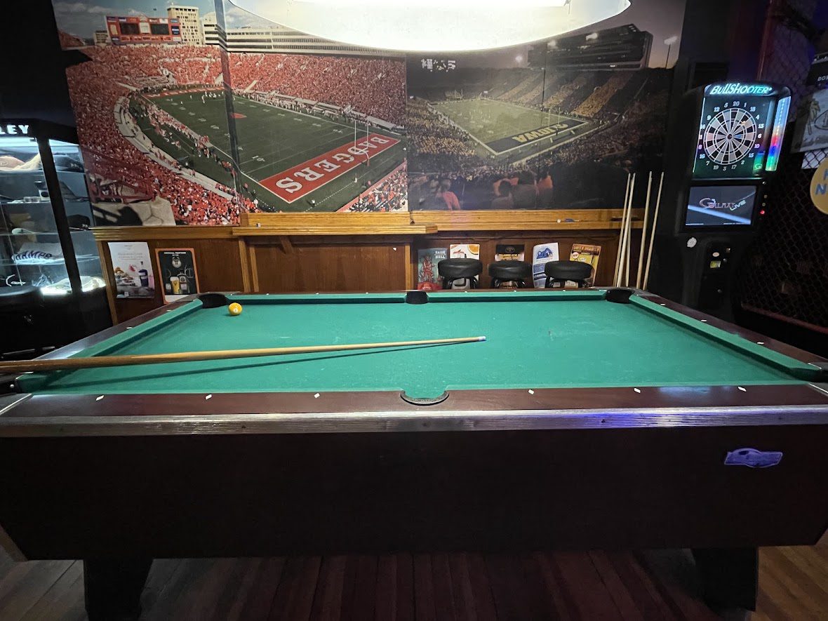 A pool table in a sports-themed room with football field posters.