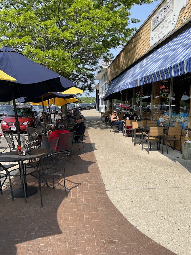 Outdoor seating area with colorful umbrellas along a sunny sidewalk.