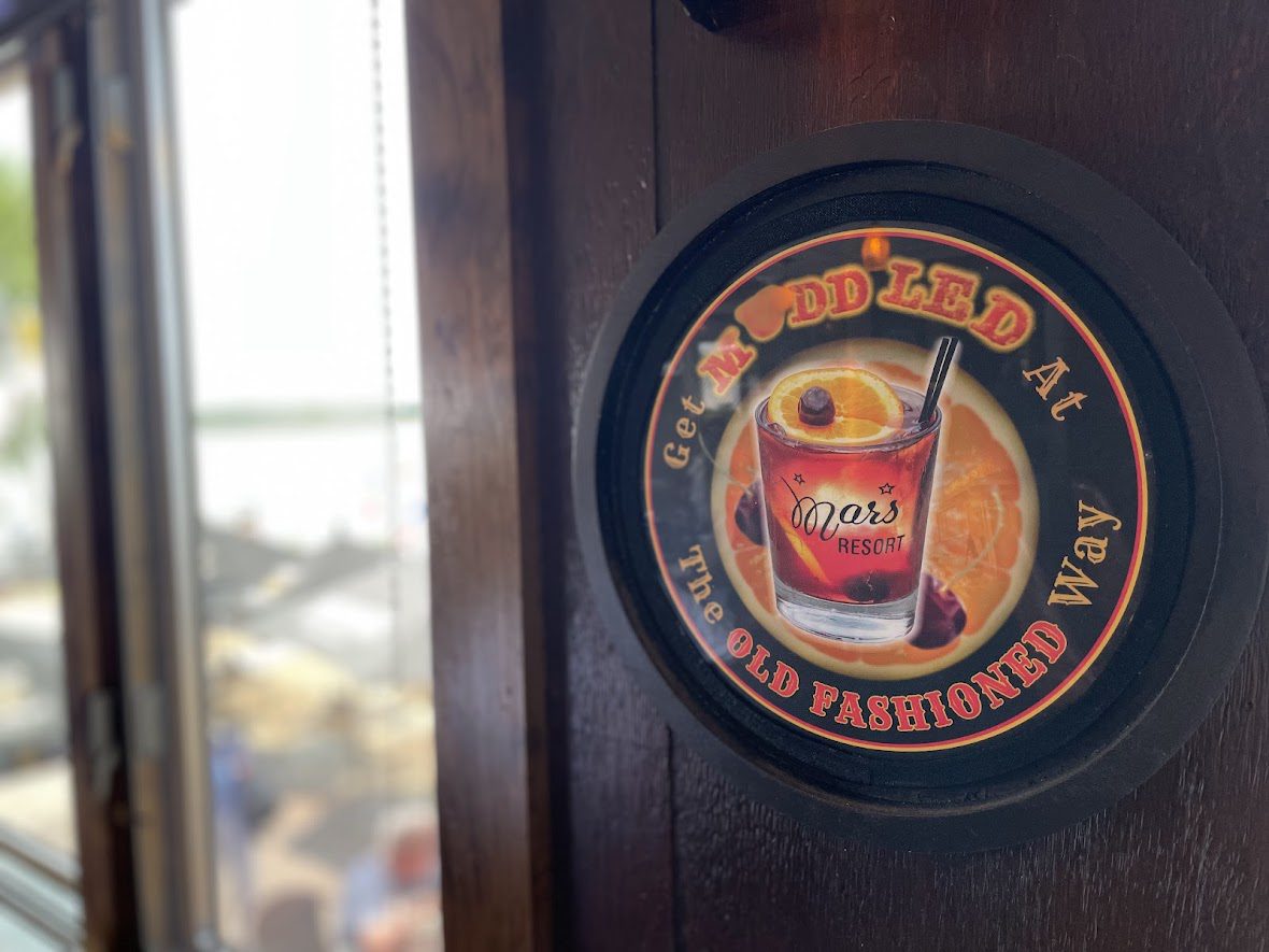 Vintage beer coaster with a red beer mug logo on a wooden surface.