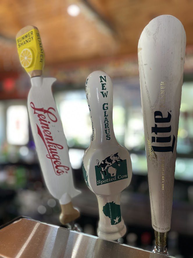 Close-up of beer tap handles featuring Budweiser, New Glarus, and Miller Lite.