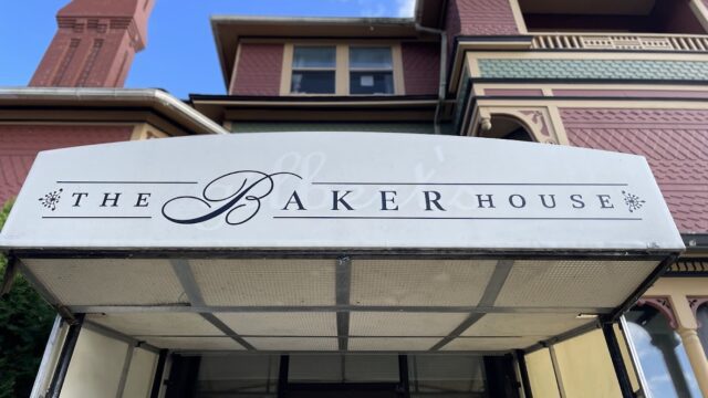 Facade of The Baker House with a white awning and clear blue sky.