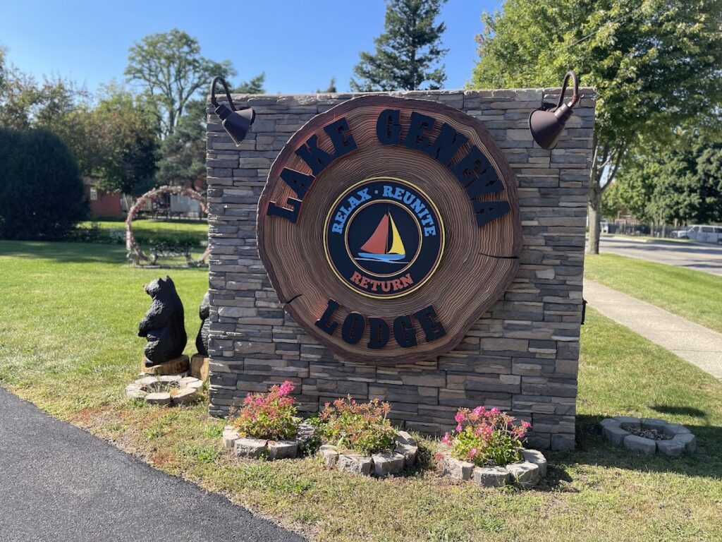 Entrance sign for Lake Lure Lodge with decorative bear and flowers.