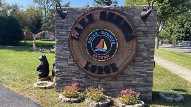 Entrance sign for Lake Lure Lodge with decorative bear and flowers.