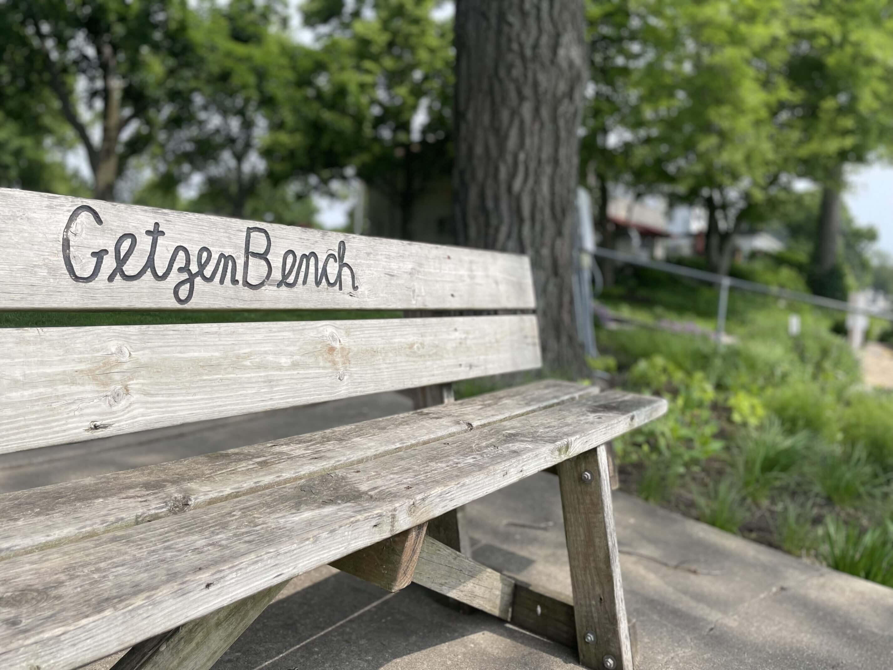 Rustic wooden bench labeled 'NetzenBanch' in a peaceful outdoor setting.