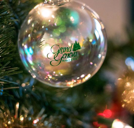 A shiny Christmas ornament with 'Merry Christmas' text on a decorated tree.