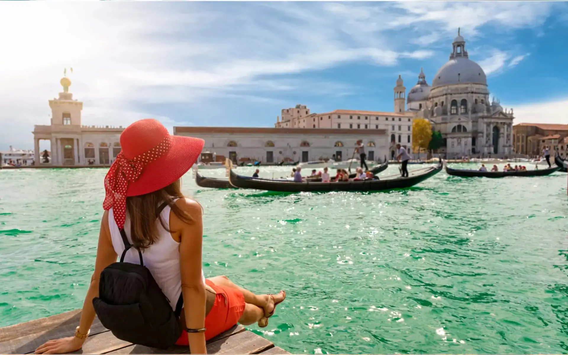 Woman in a red hat enjoying a gondola ride in Venice.
